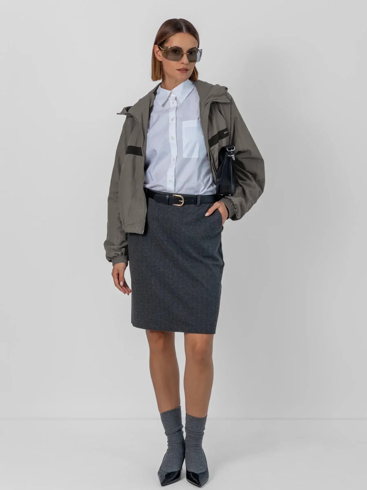 Woman wearing a PUFFLT water repellent oversized short track jacket with a white shirt and skirt.