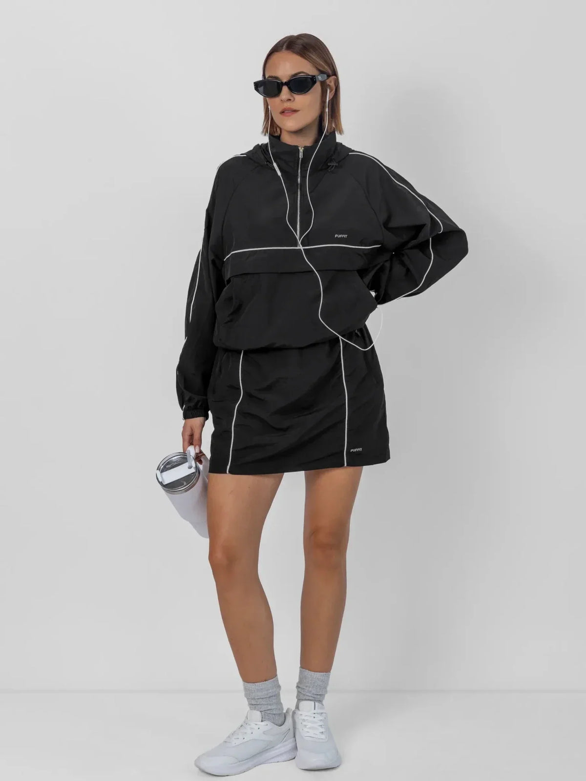 Woman wearing a PUFFLT black water repellent track skirt and matching jacket.