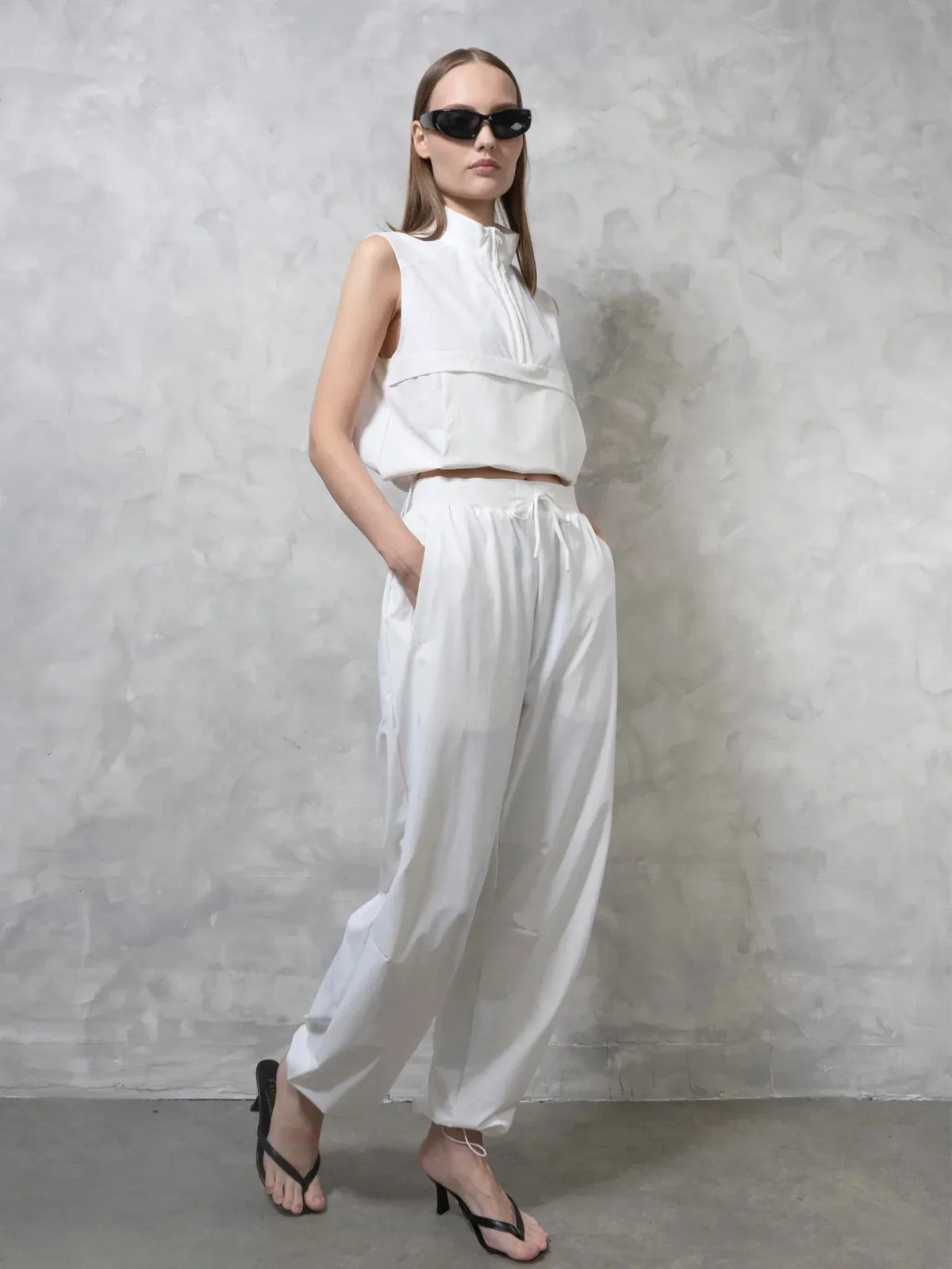 Model wearing PUFFLT high waisted drawstring utility trousers and a white sleeveless top.
